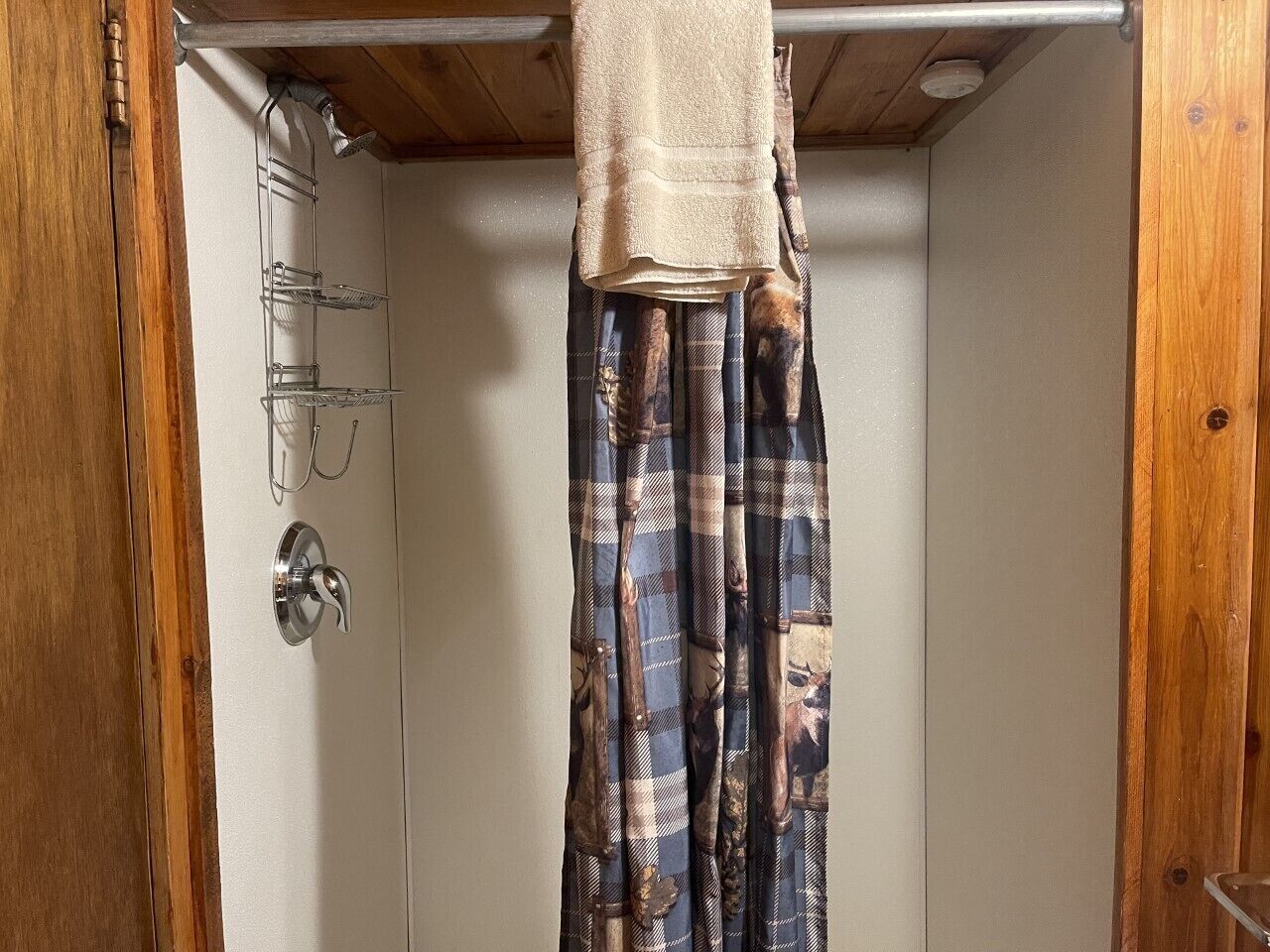 Un baño con cortina de ducha, toallero y puerta con picaporte plateado.