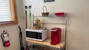 A kitchen with a microwave, coffee maker, and storage shelves. - Red River Condo #4 near Main Street (Red River)