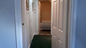 A narrow hallway with white walls, a green carpet, and white doors leading to a room. - 1 Bed Flat - Sleeps 4 - Garden - Parking - Wifi (Inverness)