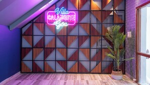 A modern interior with a neon sign reading "Villa Calangute Goa," a geometric wooden partition, and a potted plant. - Villa Calangute Phase 11 (Calangute)