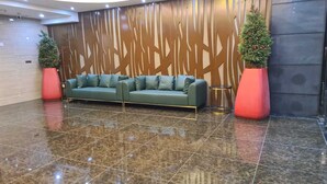 A lobby with a green sofa, two potted plants, and a decorative wall. - HOTEL EXPRESS (Luanda)