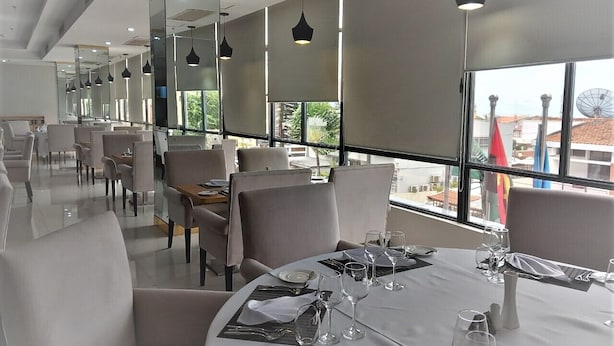 A restaurant with round tables set for dining, large windows with a view, and pendant lighting. - HOTEL EXPRESS (Luanda)