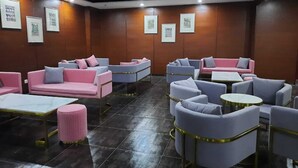 A modern lounge area with sofas and armchairs, a coffee table, and framed pictures on the walls. - HOTEL EXPRESS (Luanda)
