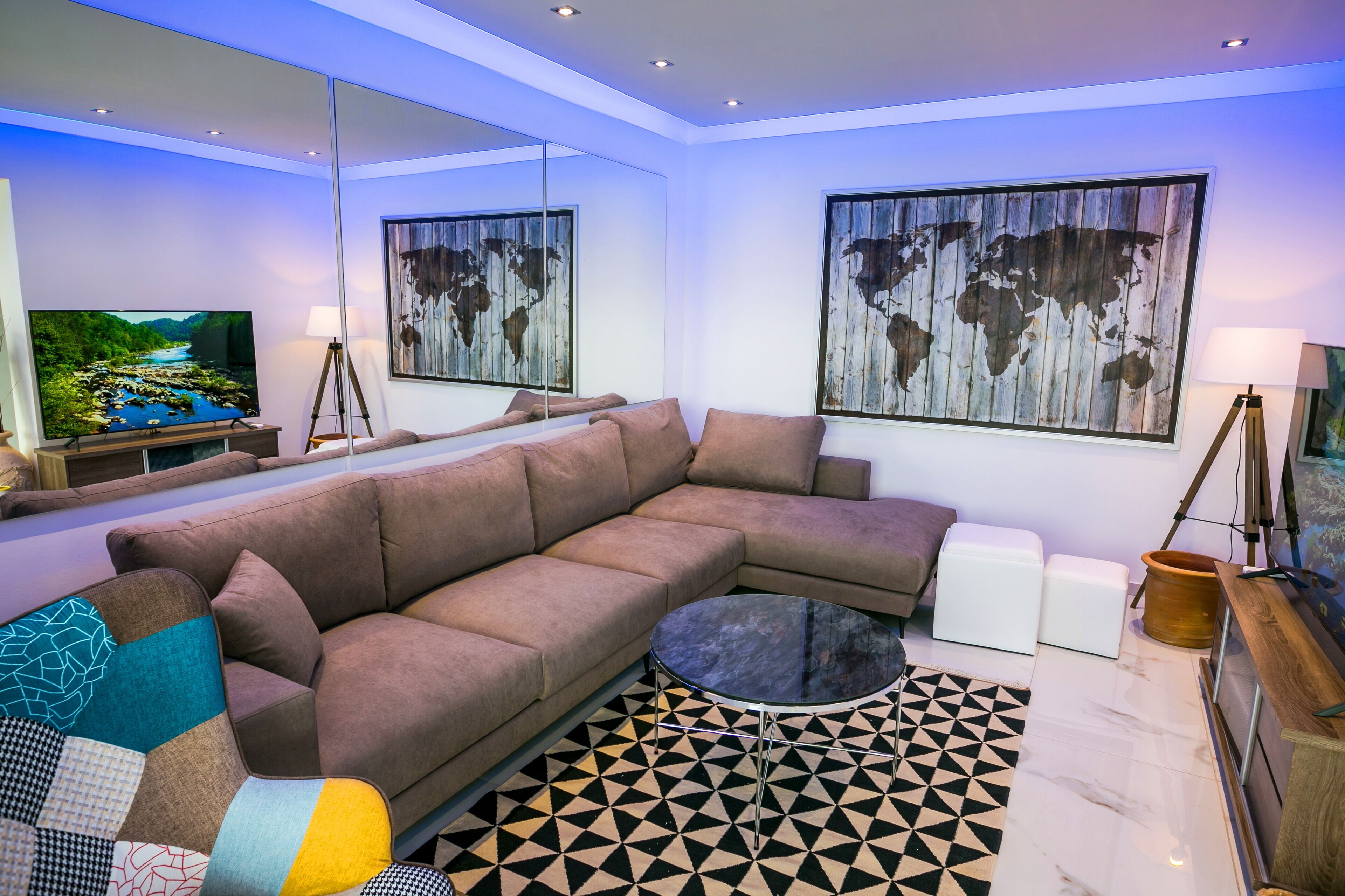 Een moderne woonkamer met een hoekbank, een ronde salontafel en een wereldkaart schilderij.