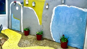 Pared pintada de colores con plantas en macetas y luces colgantes.
