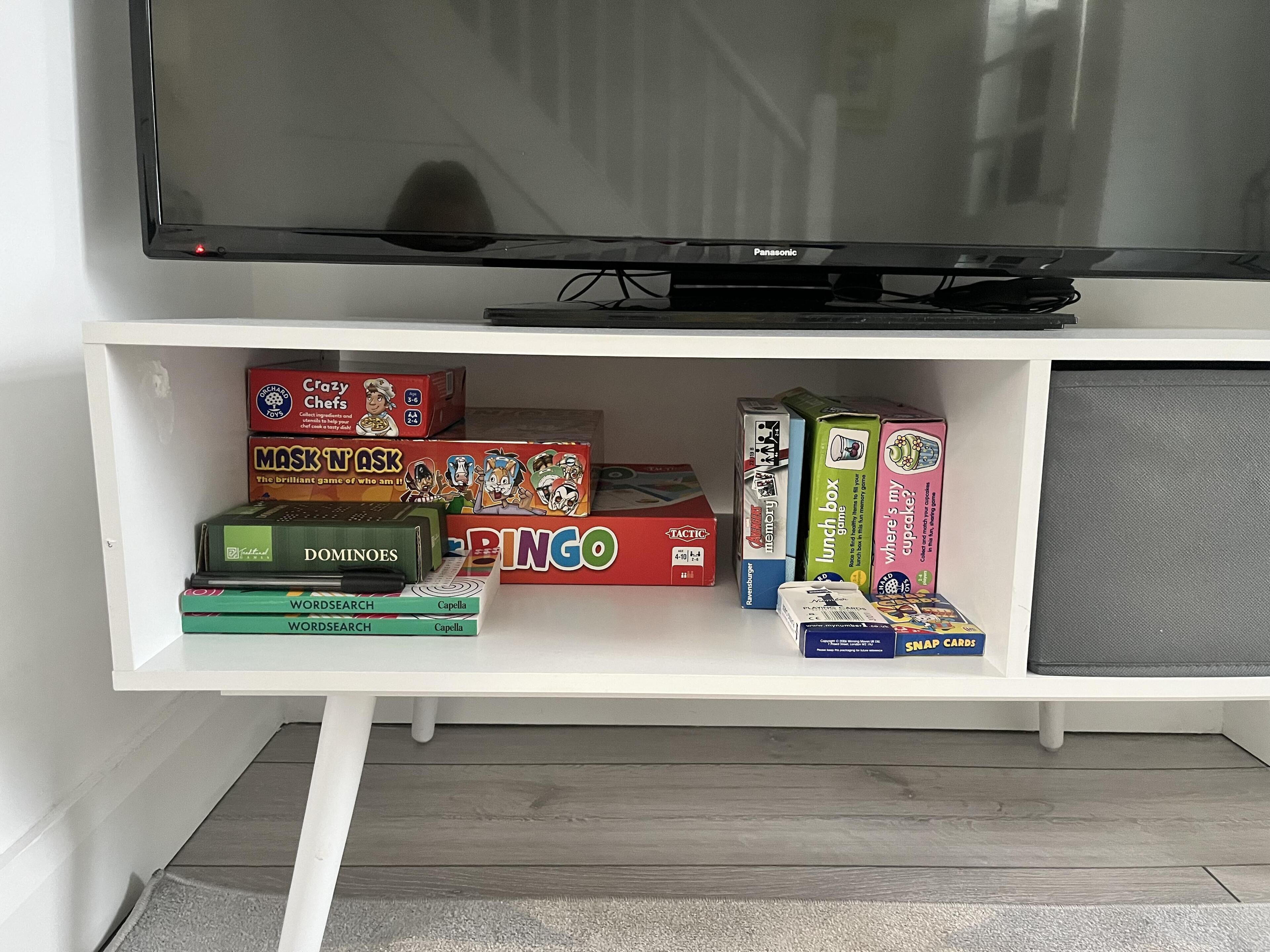 A white entertainment unit with a television and various board games.