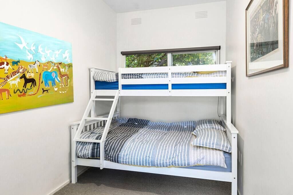 Ein Stockbett mit Fenster, ein Tiergemälde und ein gerahmtes Bild an der Wand.