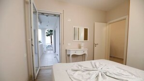 Una habitación de hotel con una cama, una mesita de noche, un espejo y una puerta que da a otra habitación.