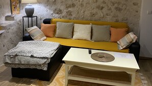 Ein Wohnzimmer mit einem gelben Sofa, einem gemusterten Teppich und einem weißen Couchtisch.