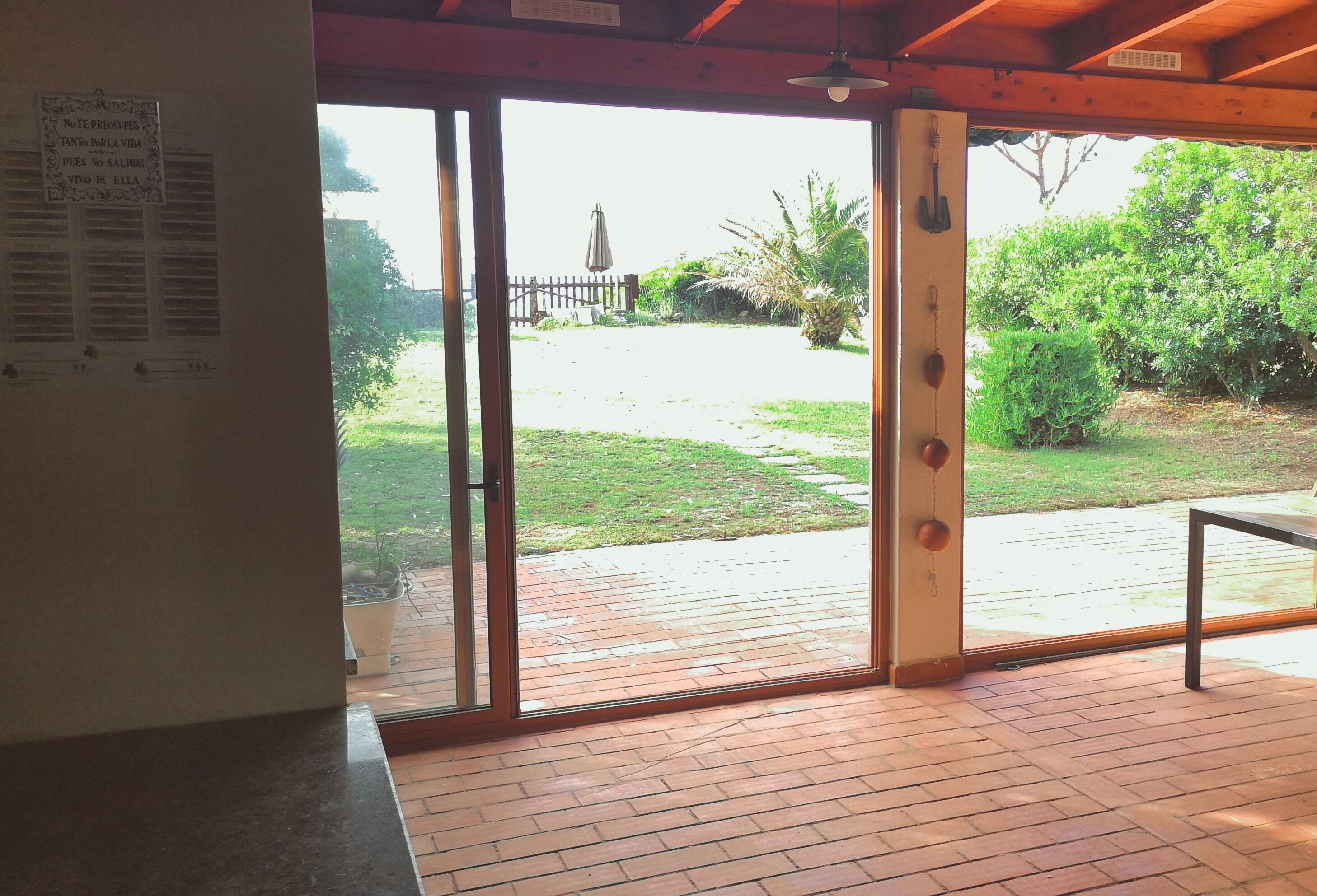 A room with a brick floor, a sliding glass door leading to a patio, and a wooden ceiling.