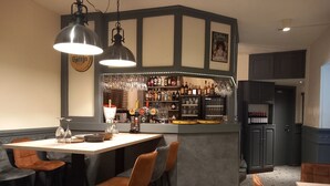 Een bar met krukken, een toonbank vol flessen en een aan de muur hangend schilderij.