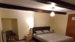 Een slaapkamer met een bed, nachtkastje, stoel en een hanglamp.