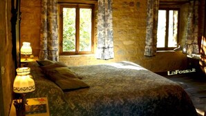 A rustic bedroom with a large bed, two windows with curtains, and a lamp on a bedside table. - Romantic house in the woods - lafossa.eu
Breakfast included (Vetto)