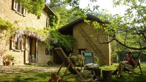 A rustic stone building with a sloped roof and a wooden swing set in the yard. - Romantic house in the woods - lafossa.eu
Breakfast included (Vetto)