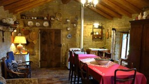 A rustic dining area with a wooden table set for four, a chandelier, and stone walls. - Romantic house in the woods - lafossa.eu
Breakfast included (Vetto)
