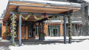 Un bâtiment moderne doté d’une façade en bois et d’un espace d’entrée abrité, décoré de guirlandes de verdure et d’un nœud rouge.