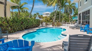 A pool area with blue chairs, palm trees, and a clear blue sky. - Sombrero Beach Beauty~ 50` Dock Private Pool Home! (Marathon)