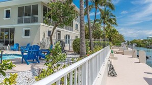 A two-story building with a pool, blue chairs, and palm trees. - Sombrero Beach Beauty~ 50` Dock Private Pool Home! (Marathon)
