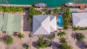 An aerial view of a coastal property with a swimming pool, multiple buildings, and palm trees. - Sombrero Beach Beauty~ 50` Dock Private Pool Home! (Marathon)