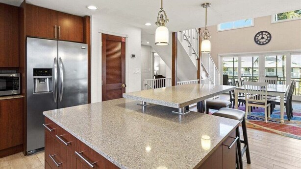 A modern kitchen with a stainless steel refrigerator, granite countertops, and a central island. - Sombrero Beach Beauty~ 50` Dock Private Pool Home! (Marathon)