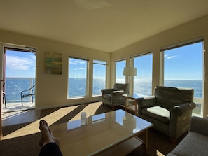 Relax in a spacious living area with ocean views, a large table, and comfortable seating for two.