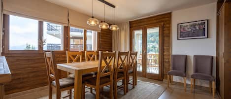 Un espace repas comprenant une table et des chaises en bois, un tapis et une vue sur l’extérieur.