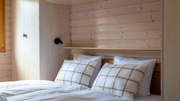 A bed with two pillows, a wooden headboard, and a white wall.