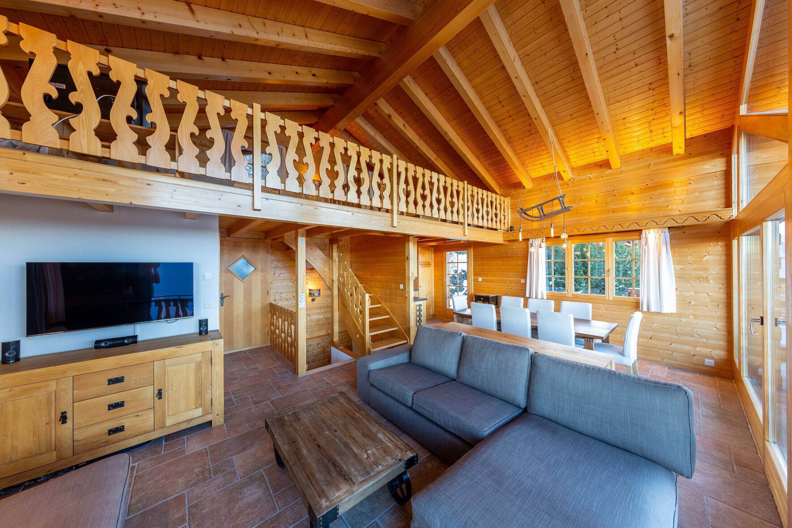 Un intérieur spacieux en bois, avec un grand canapé, un téléviseur et un coin repas.