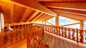 Ein Holzinnenraum mit einem Balkon mit Blick auf eine Berglandschaft.