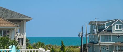 A coastal residential area with houses, a clear blue sky, and the ocean in the background.