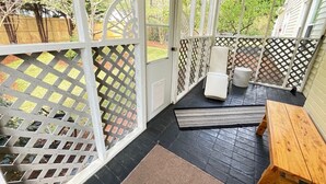 Un patio abrité avec un banc en bois, un fauteuil rembourré et une petite table.