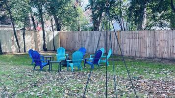 A backyard with a swing set, blue chairs, and a table.