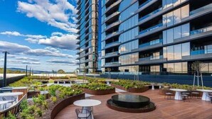 A modern building with multiple floors, outdoor seating areas, and a rooftop garden. - Modern Luxury 2B2B Sky Garden SmartTV (Glen Waverley)
