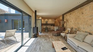 Un salon moderne doté d’une grande porte vitrée donnant sur un espace extérieur, d’une cheminée et d’un coin salon confortable.