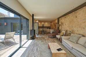 Una sala de estar moderna con un gran ventanal que da a un espacio exterior, una chimenea, un sofá y una mesa de centro.