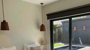 Une chambre moderne avec un grand lit, deux lampes suspendues, une vue sur une piscine et une porte-fenêtre coulissante.