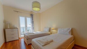A hotel room with two beds, a dresser, a lamp, and a view of the outside. - FLH Garajau Fantastic Ocean View with Balcony (Santa Cruz)