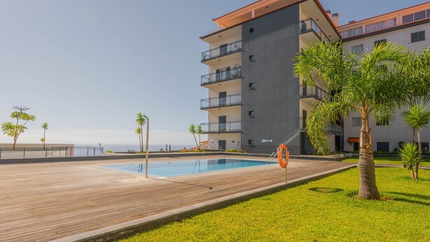 A modern building with a pool, balconies, and a wooden deck. - FLH Garajau Fantastic Ocean View with Balcony (Santa Cruz)