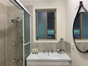 Ein Badezimmer mit Dusche, Waschbecken und Fenster.