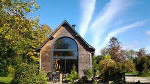 A small, single-story house with a pitched roof and a large arched window.