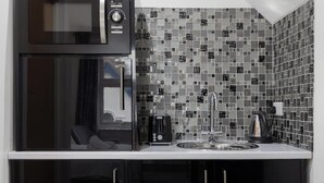 A compact kitchenette with a black refrigerator, microwave, and coffee maker.