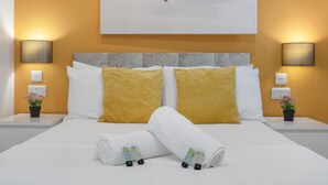 A neatly made bed with white and yellow pillows, two bedside tables with lamps, and a wall-mounted artwork. - Central and Modern One Bedroom Flat (Oxford)