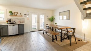 Een moderne keuken met grijze kastjes, een houten eettafel en een bank.