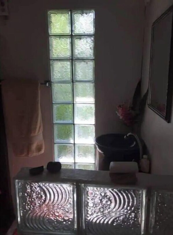 Une salle de bain avec une fenêtre en verre dépoli, une serviette accrochée au mur et un lavabo avec un miroir.