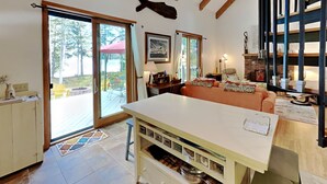 A kitchen with a large island, a dining area with a table and chairs, and a view of the outdoors through a sliding glass door. - Wolfe's Way Priv. Beach, Waterfront recreation, Swim & Acadia! (Franklin)