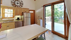 A kitchen with a large island, wooden cabinets, a stainless steel refrigerator, and a view of a deck through a glass door. - Wolfe's Way Priv. Beach, Waterfront recreation, Swim & Acadia! (Franklin)