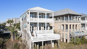A multi-story building with balconies and a covered walkway, surrounded by vegetation and other buildings. - Aqua Easy - Destin Pointe, Gulf Views, Lakefront, Free Beach Service, Cmty Pool! (Destin)