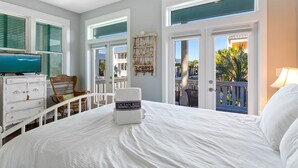 A bedroom with a bed, a dresser, a chair, a television, and a view of the outside. - Aqua Easy - Destin Pointe, Gulf Views, Lakefront, Free Beach Service, Cmty Pool! (Destin)