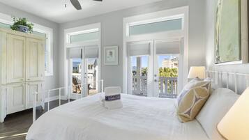 Une chambre avec un grand lit, un ventilateur de plafond et une vue sur le balcon.