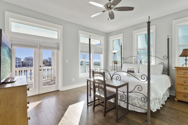 A bedroom with a bed, a desk, a chair, a dresser, and a ceiling fan.